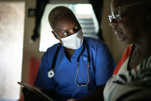 Health visitor and a senior woman during home visit - using digital tablet