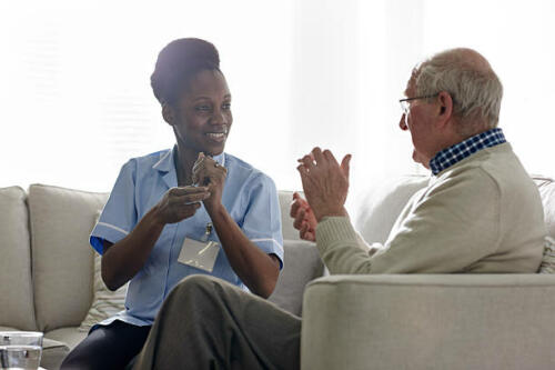 Female theropist carrying out tapping session with a senior client at home